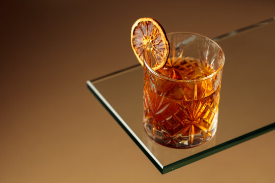 Old-fashioned cocktail with ice and a dried orange slice.
