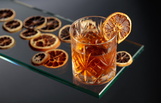 Old-fashioned cocktail with ice and a dried orange slice.