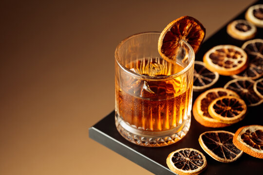 Old-fashioned cocktail with ice and a dried orange slice.
