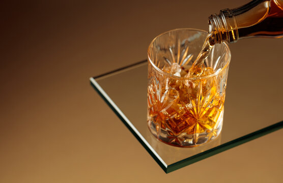 Whiskey is poured into a glass with ice.
