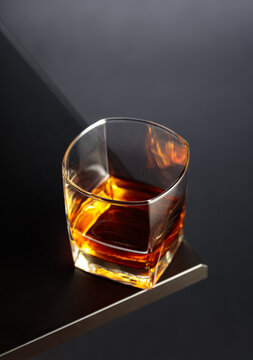 Glass of whiskey on a black table.