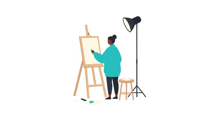 Fototapeta premium Artist wearing a blue sweater working on a painting on an easel illuminated by a large studio lamp in a white room setting.