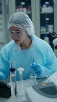 Female scientist in a cleanroom conducting plant research using a microscope and laboratory equipment for biotechnology