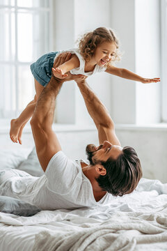 A happy family moment with a father and daughter on a bed.