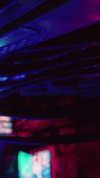 The scene shows a lively nightclub with colorful lights illuminating the space. People enjoy music while moving under bright, flashing colors. The atmosphere is energetic and engaging.