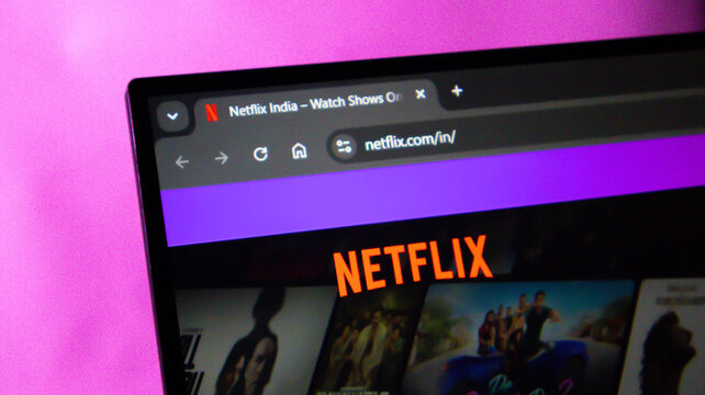 Close-up of laptop screen displaying Netflix India website with purple and pink reflections