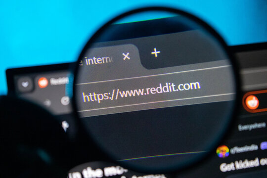 Magnifying glass over Reddit website URL on a computer screen with blue background light