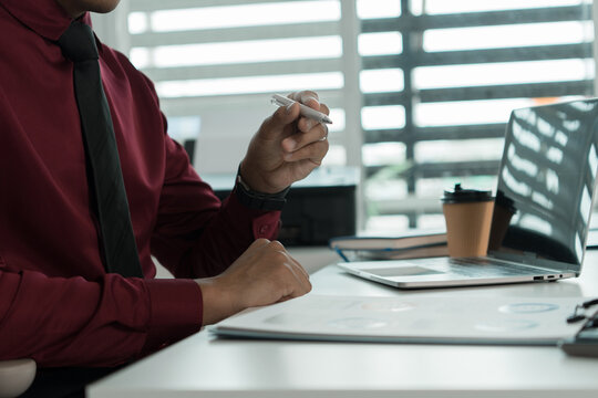 Focused Asian Businessman Reviewing Documents at Office Desk