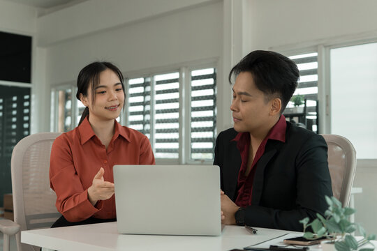 Business Colleagues Discussing Project at Office Desk with Laptop