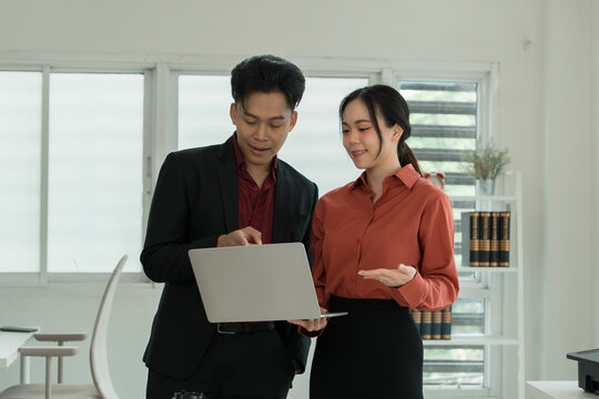Business Colleagues Standing and Discussing Project on Laptop in Office