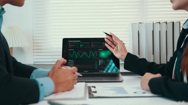 Business colleagues analyzing financial data on a laptop screen during a corporate meeting in the office for investment planning