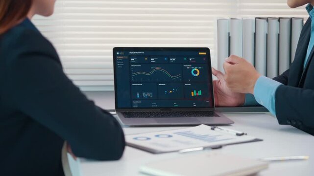 Business colleagues analyzing financial data dashboard and company performance on a laptop during a strategic meeting in the office