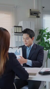 Confident businessman presenting a growth chart during a meeting with a female colleague in the office