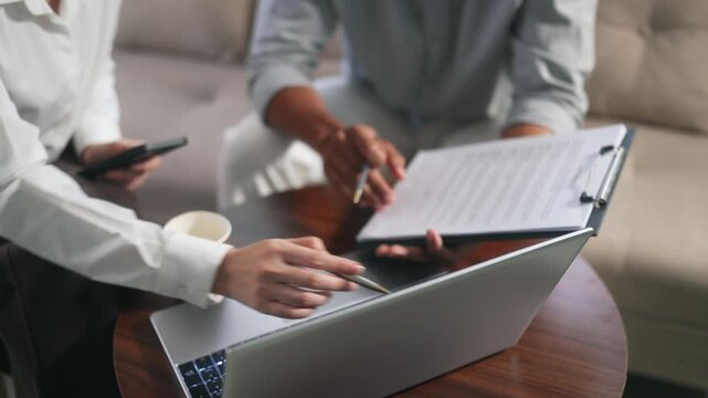 Business people collaborating on project analyzing data from contract documents and laptop computer during office meeting