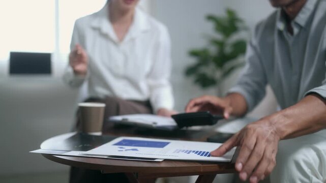 Financial advisor calculating expenses and explaining investment plan to a male client during a consultation at home