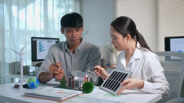 Engineers discussing clean energy solar panel installation for sustainable house model in an innovative office meeting