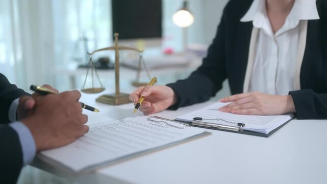 Female lawyer showing a client where to sign a legal contract document for a court case in the law office