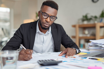 Fototapeta premium Focused Businessman Working on Financial Reports with Calculator