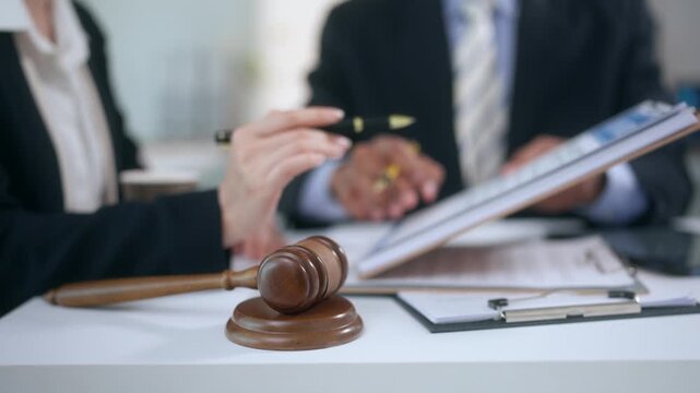 Judge's gavel on the desk with lawyers discussing a legal case in the background during a consultation