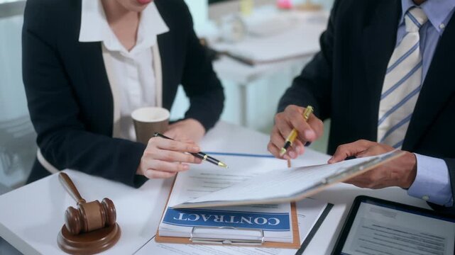 Lawyer explaining legal contract terms to a client before signing the document in a law office meeting with a gavel
