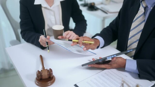 Lawyers consulting and discussing contract documents with a client in a legal office. Business people reviewing a case