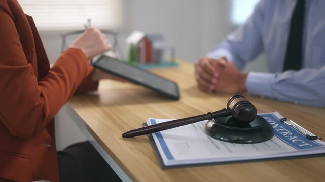 Female lawyer discussing real estate contract with client in law office with judge's gavel on the desk