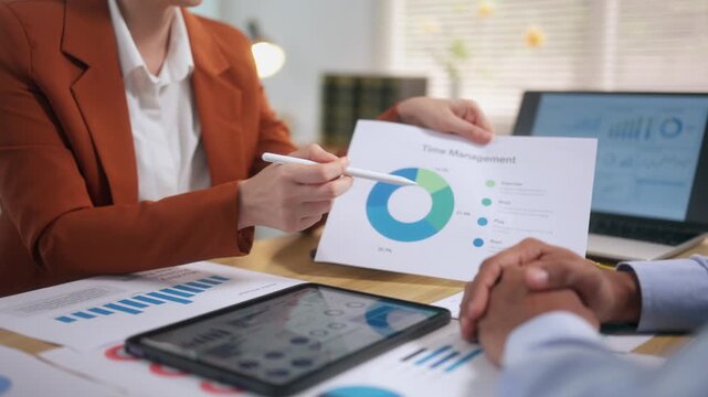 Businesswoman presenting time management pie chart data to colleague during a corporate office meeting