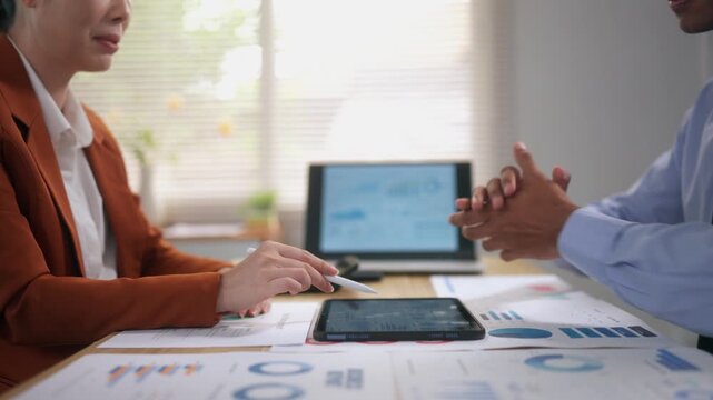 Businesswoman and businessman discussing data analysis and sealing a deal with a handshake