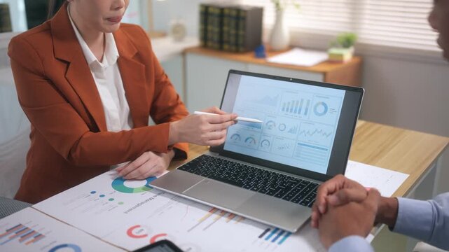 Businesswoman presenting financial data on laptop to a male colleague during a corporate meeting in the office