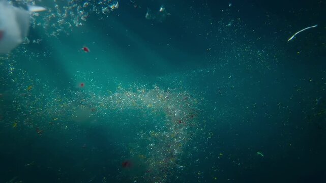 Underwater scene showing microplastics and debris dispersed in ocean water