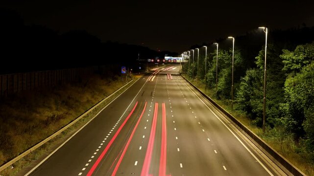 A Time-Lapse Shot of Traffic Light Trails on a British Motorway at Night, Showing Illuminated Overhead Gantry Signs Directing Traffic to Heathrow Airport, Gatwick Airport, and the M4