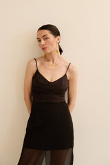 Obraz premium Chic woman showcases elegance in stylish black attire against a soft background