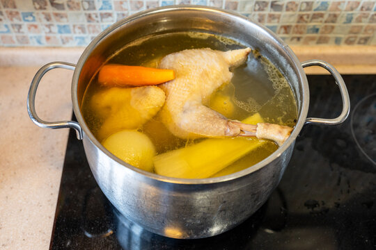 chicken broth is cooking with vegetables in pot