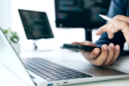 Software Developer Testing Mobile Application Interface on Smartphone, Reviewing Source Code on Laptop for Cross Platform App Development, Debugging, Quality Assurance, User Experience Validation