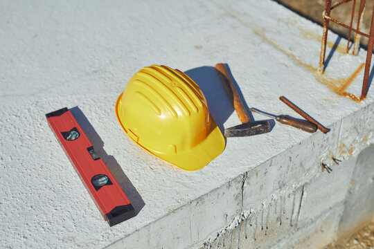 Construction tools and helmet on a cement foundation with iron rebar.