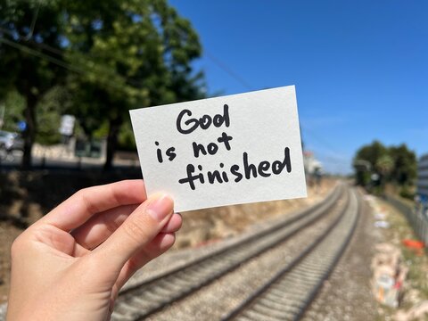 God is not finished - hand with christian note outdoors, biblical motivation about trusting Lord 