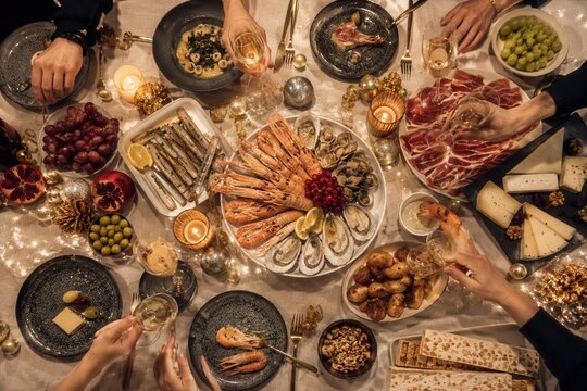 Festlicher spanischer Silvestertisch von oben mit Meeresfr&uuml;chten, Trauben, Cava, Schinken, K&auml;se und Kerzenlicht, luxuri&ouml;se Nochevieja-Tafel f&uuml;r Familie und Freunde.