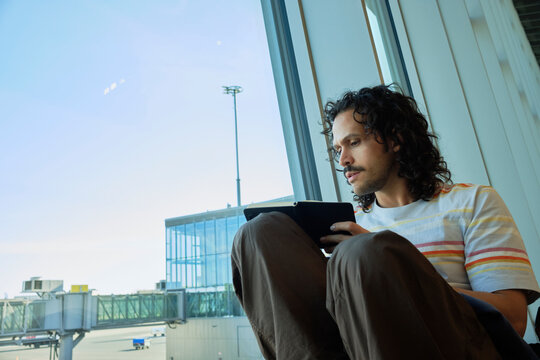 Man writing on notebook beside airport terminal windows