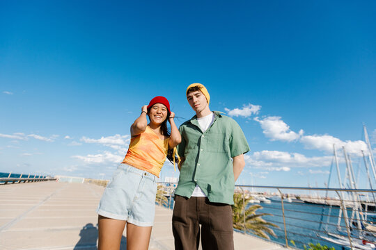 Young multi ethnic couple relaxing by waterfront marina