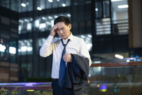 Stressed businessman leaving office at night in urban business district