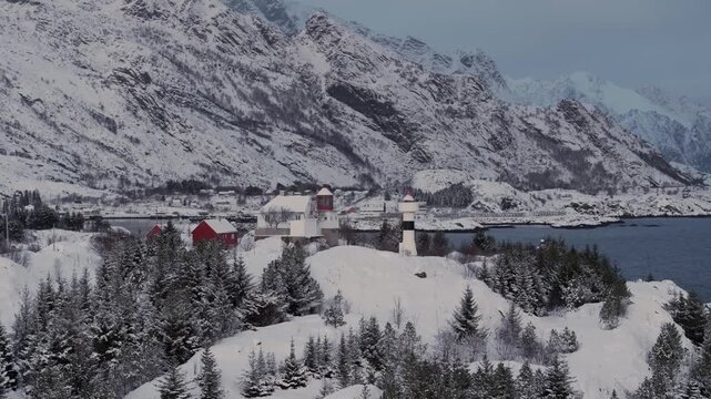 Aerial view of snowy coastal village with lighthouse on rocky promontory