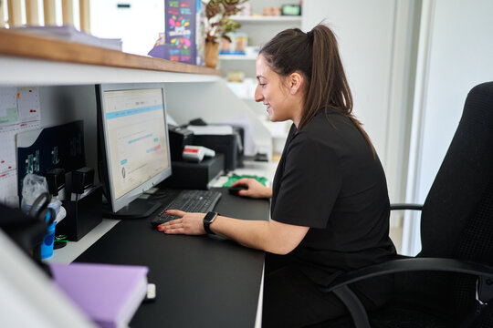 Woman working on computer at veterinary clinic reception desk