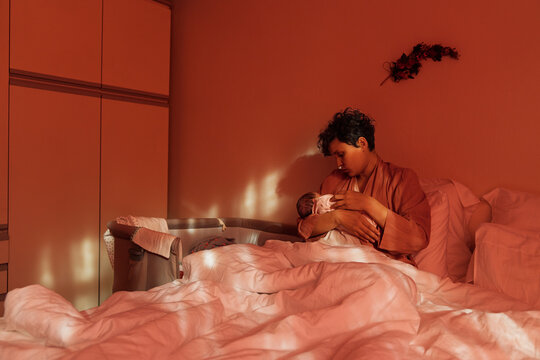 Real moment of a mother tenderly holding her baby in bed