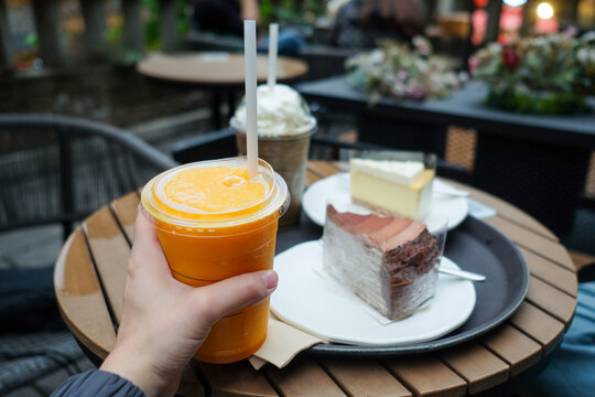 Hand Holding Orange Juice at Cafe