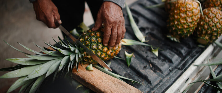 Person peeling tropical fruit preparing it for healthy food or juice