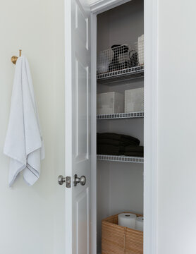 Organized Linen Closet with Folded Towels and Woven Storage Basket