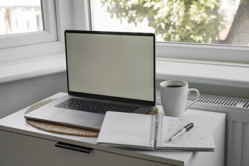 Fototapeta premium Laptop with blank screen, notebook and coffee on home office desk