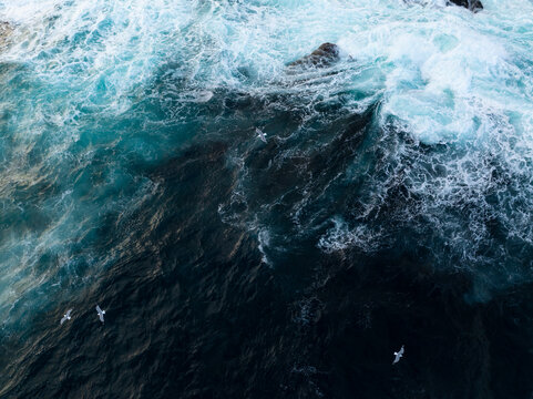 Aerial view of dark ocean waves and white sea foam