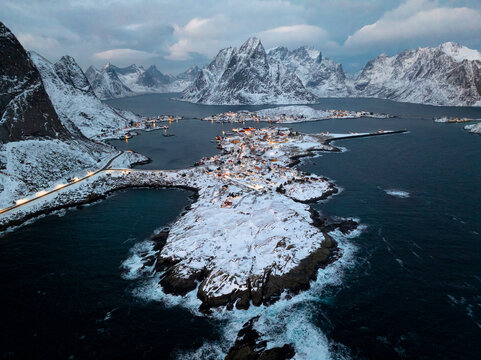Snowy coastal village surrounded by dramatic mountain fjord