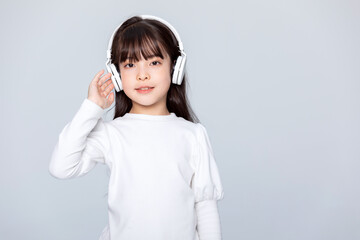 Fototapeta premium Little girl listening to music with headphones in studio portrait